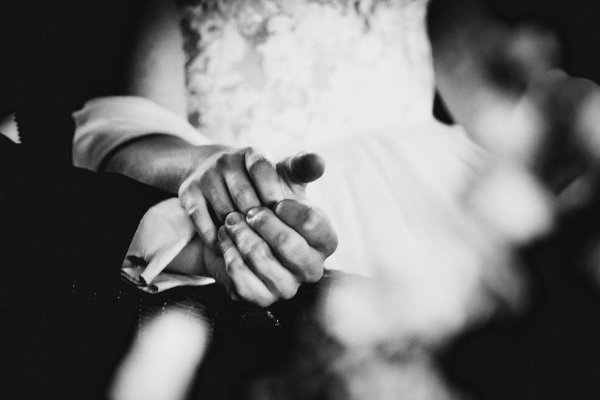 Bräutigam hält die Hand der Braut während der kirchlichen Trauung