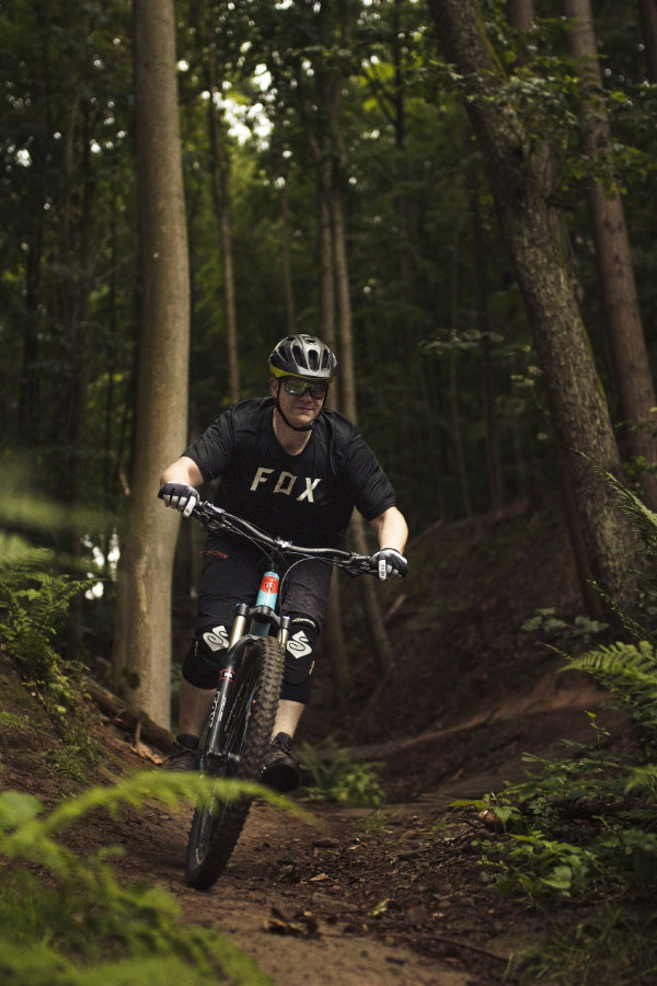 Mann fährt mit Mountainbike eine leichte Abfahrt in Richtung Kamera durch den Wald in Miltenberg.