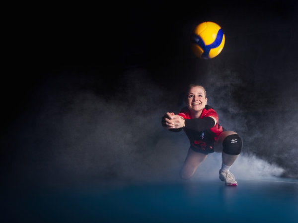 Volleyball Spielerin baggert einen Ball, im Hintergrund ist Nebel zu sehen.